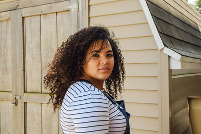 Portrait of young woman standing against building