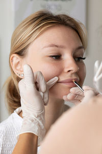 Close-up of young woman applying make-up at home