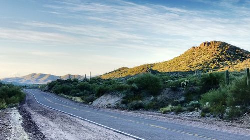 Scenic view of road by mountain against sky