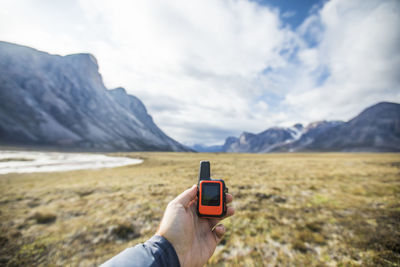 Adventurer holds mini gps and satellite safety communication device.