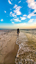 Rear view of person on beach against sky