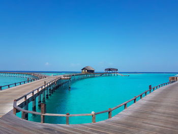 Pier over sea against clear blue sky