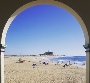 People on beach against clear blue sky