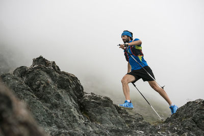 Rear view of man on rock against sky