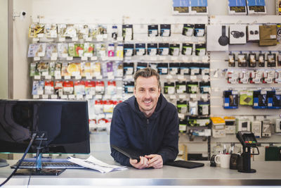 Portrait of confident smiling entrepreneur in computer store