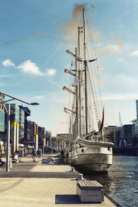 Sailboats moored at harbor against sky