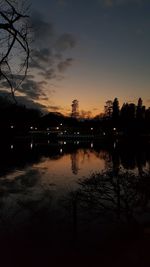 Silhouette trees by lake against sky during sunset