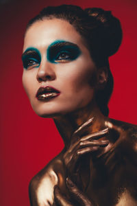 Close-up of young woman with make-up against red background