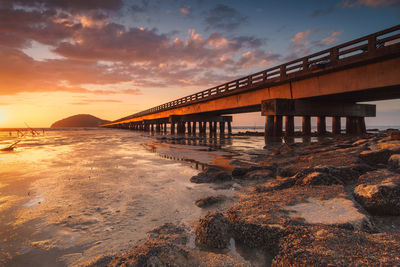 Bridge over sea against sky during sunset