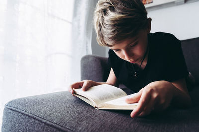 Midsection of man reading book at home