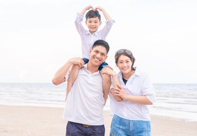 Happy family enjoying at beach against sky