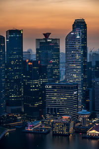 Illuminated buildings in city against sky during sunset