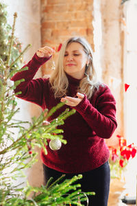 Portrait of smiling young woman holding plant in winter