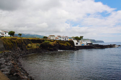 Scenic view of river by buildings against sky