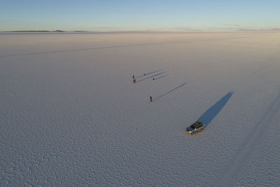 People and their elongated shadows while photographing the salar