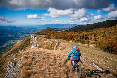 Woman mountain biking on footpath near ridge on mount nanos above vipava, slovenia.