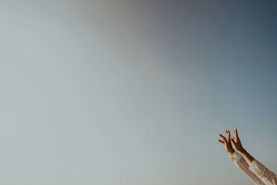 Cropped hands of woman reaching clear sky