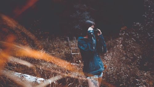 Woman standing on field in forest