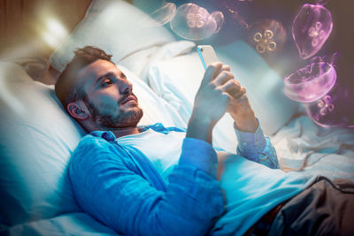 Double exposure of man using phone on bed and jellyfishes in water