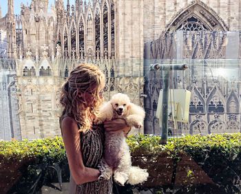 Woman holding dog standing outdoors