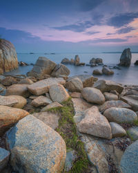 Rocks on beach against sky during sunset