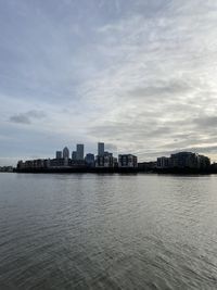 Sea by buildings against sky in city