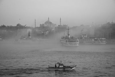 Boat sailing in sea against sky in city