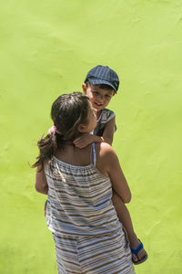 Rear view of friends standing against green wall