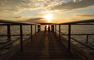 Pier on sea against sky during sunset