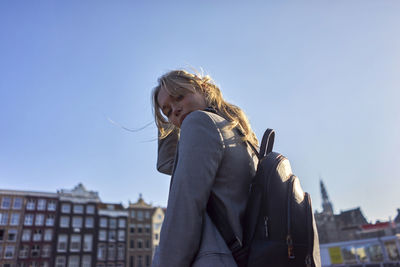 Portrait of woman standing against clear sky in city