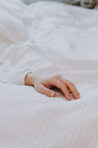 Cropped hand of woman on bed