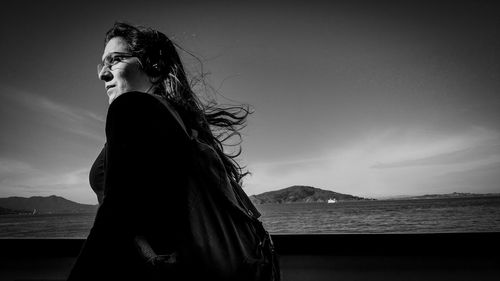 Woman with arms raised standing against sky