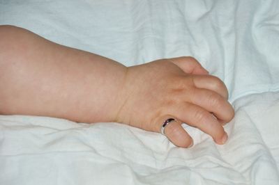 Close-up of person hand on bed