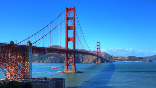 Suspension bridge over river against blue sky