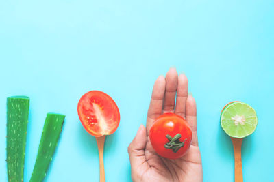 Midsection of person holding fruits against blue background