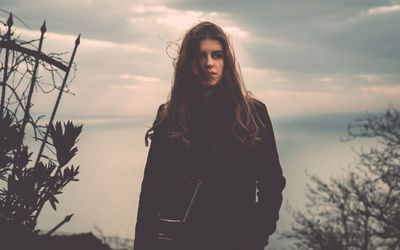 Young woman standing against sky