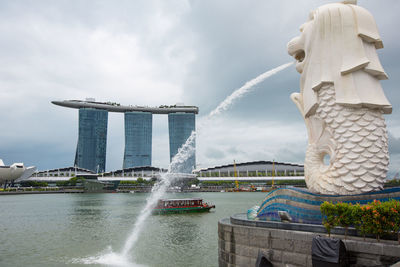 Fountain in front of sea against cloudy sky