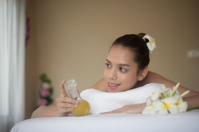 Smiling young woman with oil lying on massage table in spa