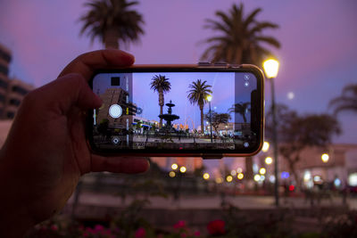 Hand photographing through smart phone at sunset