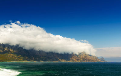 Scenic view of sea and mountains against blue sky