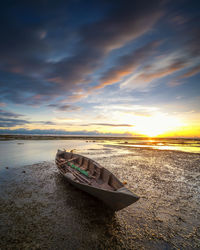 Boat moored on sea against sky during sunset