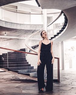 Full length portrait of young woman standing against wall