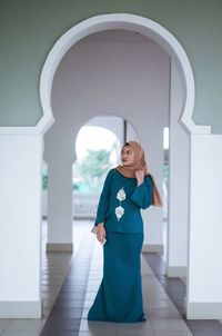 Young woman in hijab standing at archway