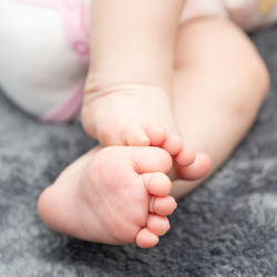 Low section of baby lying on bed