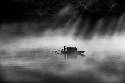 Silhouette man on boat sailing in lake