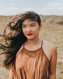 Portrait of beautiful young woman standing against sky