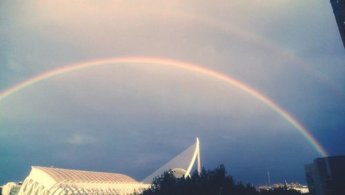 Low angle view of rainbow over buildings against sky
