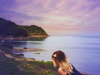 Woman on beach against sky during sunset