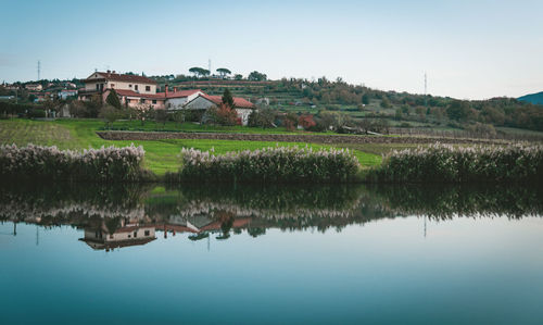 Scenic view of lake by houses against sky