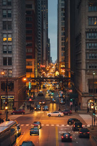 Vehicles on road amidst buildings in city at night